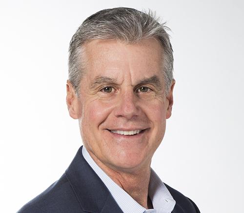 a man wearing a suit and tie smiling at the camera