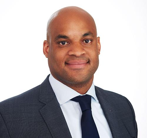 a man wearing a suit and tie smiling at the camera