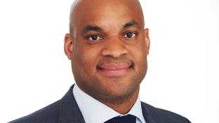 a man wearing a suit and tie smiling at the camera