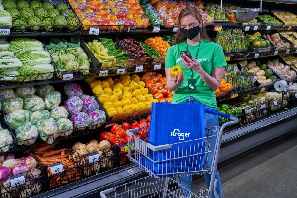 a person standing in front of a store filled with lots of produce