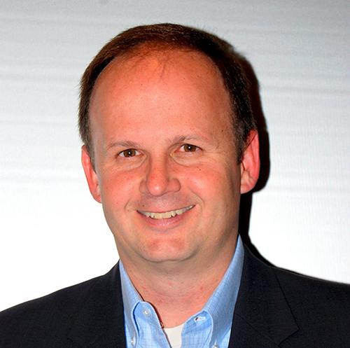 a man wearing a suit and tie smiling at the camera