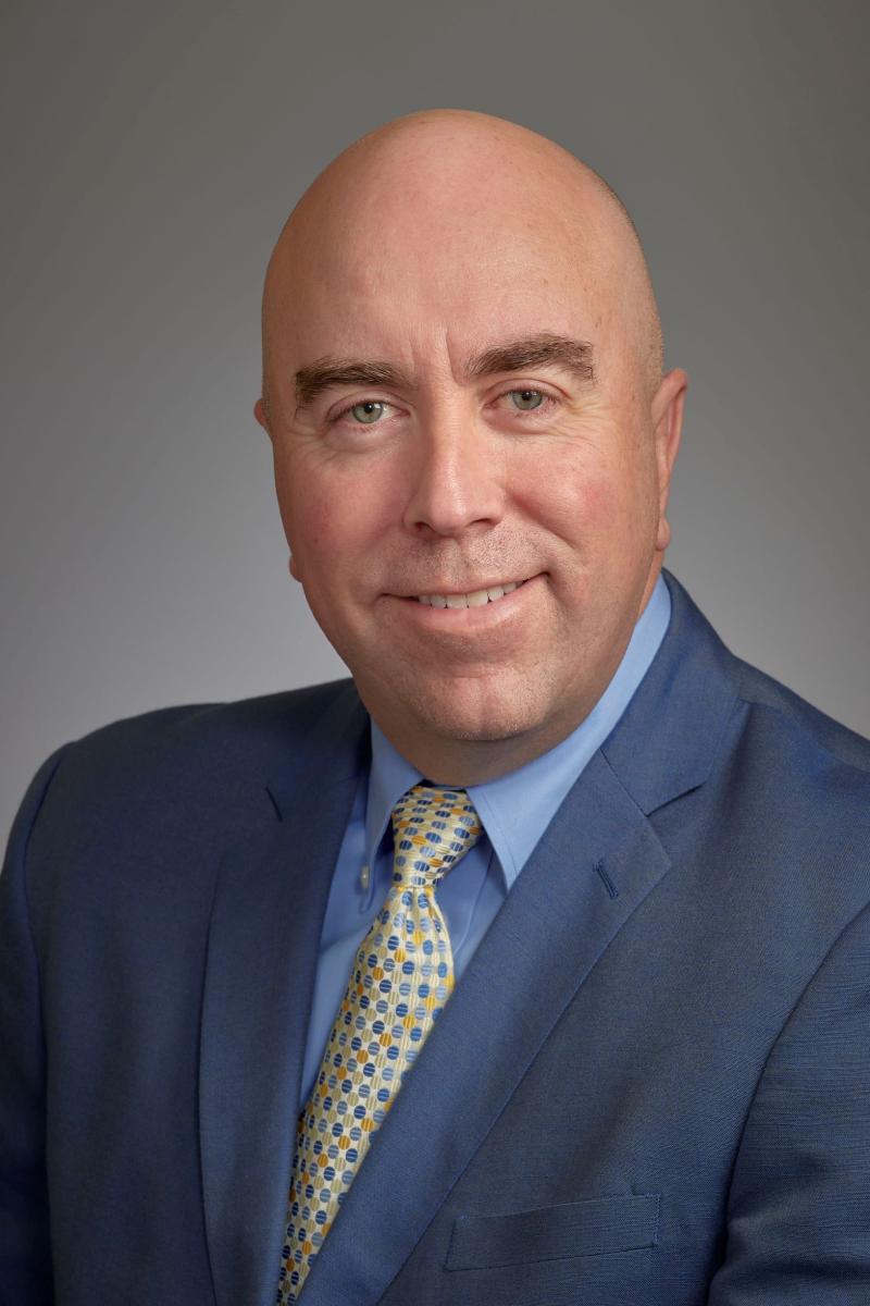 a man wearing a suit and tie smiling at the camera