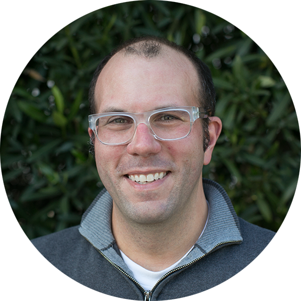 a man wearing glasses and smiling at the camera